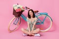 Full length photo of lady sit floor crossed legs bunch flower bike wear trendy dress footwear on pink color