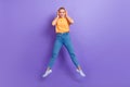 Full length photo of lovely cute girl dressed jeans white sneakers jumping hands touch headphones isolated on violet Royalty Free Stock Photo
