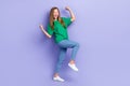 Full length photo of lucky funny girl dressed green t-shirt walking rising fists isolated purple color background Royalty Free Stock Photo