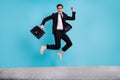 Full length photo of lucky pretty man wear black suit case jumping high celebrating summer journey isolated blue color Royalty Free Stock Photo