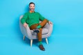 Full length photo of mature nice mister sitting comfy soft armchair relaxing dressed stylish green look isolated on blue Royalty Free Stock Photo