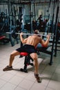 A sports guy doing exercise with a big barbell on a bright gym background. A bodybuilder training in a fitness club. Royalty Free Stock Photo