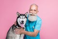 Full length photo of nice good doctor old man dressed blue uniform stethoscope on neck cuddle husky isolated on pink