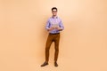 Full length photo of nice successful man dressed trendy outfit using modern gadget isolated on beige color background