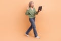 Full length photo of nice woman khaki cardigan walk empty space with laptop waving hand on video call isolated on beige