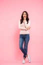 Full length photo of nice woman with long brown hair looking upward with guilty or shy sight, isolated over pink background