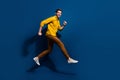 Full length photo of nice young male jumping run black friday promo wear trendy yellow garment isolated on dark blue Royalty Free Stock Photo