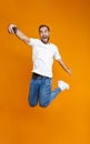 Full length photo of optimistic guy 30s in casual wear laughing and taking selfie on cell phone, isolated over yellow background