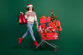 Full length photo of overjoyed person hold packages push trolley jumping isolated on green color background