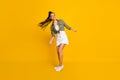 Full length photo portrait of cute girl swinging hair isolated on vivid yellow colored background