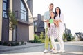 Full length photo of positive adorable family hands hold paper house card toothy smile look camera spend time outdoors Royalty Free Stock Photo