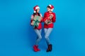 Full length photo of positive charming women santa elves wear ornament pullovers preparing x-mas gifts isolated blue