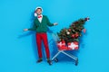 Full length photo of positive cheerful guy dressed xmas green cardigan rising hands arms shoppers buyer isolated blue
