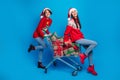 Full length photo of positive cute women santa elves wear ornament pullovers buying x-mas gifts isolated blue color