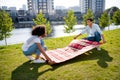 Full length photo of positive guy nice girl lay prepare picnic blanket green lawn city center park outside Royalty Free Stock Photo