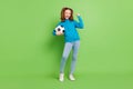 Full length photo of positive happy small girl hold hand football winner yes isolated on green color background