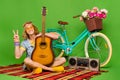 Full length photo of positive hippy guy sit plaid blanket show v-sign isolated on green color background