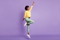 Full length photo of powerful dark skin girl jump raise fists ahead wear pullover pants isolated over purple color