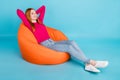 Full length photo of pretty cute lady dressed pink outfit smiling sitting bean bag arms behind head  blue color Royalty Free Stock Photo