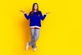 Full length photo of pretty teen girl compare empty space wear trendy knitwear blue outfit isolated on yellow color Royalty Free Stock Photo