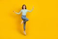 Full length photo of satisfied adorable optimistic girl striped shirt denim pants flying dancing isolated on yellow