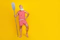 Full length photo of senior bearded masculine pensioner holding wooden boat oars looking empty space isolated on yellow