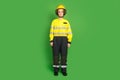 Full length photo of serious confident young firewoman dressed yellow uniform helmet isolated green color background