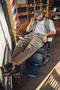 Well-dressed brunette man sitting laid-back in a barber chair