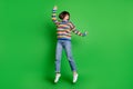 Full length photo shiny adorable young lady dressed colorful pullover jumping high smiling isolated green color