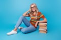 Full length photo of shiny sweet girl dressed print shirt eyewear enjoying book pile stack isolated blue color Royalty Free Stock Photo