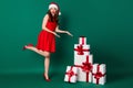 Full length photo shocked crazy girl in santa claus headwear point hand giftbox demonstrate x-mas season shopping jolly