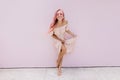 Full-length photo of slim woman with pink hair fooling around in studio. Indoor shot of barefooted