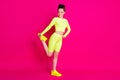 Full length photo of sportswoman stretch leg wear yellow sneakers shorts isolated on pink bright color background