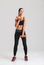 Full-length photo of sporty slim woman training in gym with small dumbbells, isolated over gray background Royalty Free Stock Photo