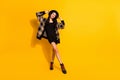 Full length photo of stunning happy positive young lady wear plaid coat mini black dress hat isolated on yellow color Royalty Free Stock Photo
