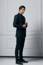 Full length photo of an stylish confident young man in black suit looking in profile, on white background. Royalty Free Stock Photo