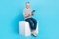 Full length photo of successful retired man sitting white cube writing texting email modern device isolated on blue Royalty Free Stock Photo