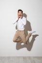 Full length photo of surprised guy in shirt and trousers jumping