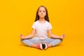 Full length photo of sweet charming school girl wear white t-shirt enjoying yoga sitting floor isolated yellow color