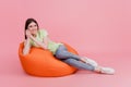 Full length photo of woman sitting in beanbag rest relax comfort isolated on pastel pink colored background Royalty Free Stock Photo