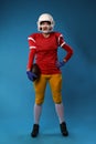 Full-length photo of young American woman football player in white helmet, sportswear with ball in her hand Royalty Free Stock Photo
