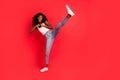Full length photo of young attractive black girl fight battle kick leg sporty isolated over red color background Royalty Free Stock Photo