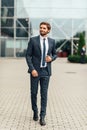 Full length photo of a young business man unbuttoning the jacket of his suit while looking away from the camera Royalty Free Stock Photo