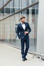 Full length photo of a young business man unbuttoning the jacket of his suit while looking away from the camera Royalty Free Stock Photo