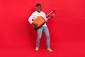 Full length photo of young cheerful male hold his heavy baggage leaving for summer vacation isolated on red color