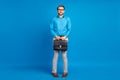 Full length photo of young funny man hold suitcase shy nervous modest isolated over blue color background