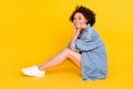 Full length photo of young happy positive afro american woman hold hands face smile sit floor isolated on yellow color Royalty Free Stock Photo