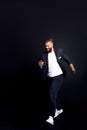 Full length photo of a young IT man with a lush beard running to work and smiling holding a phone in his hand isolated on black Royalty Free Stock Photo