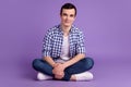 Full length photo of young man sitting floor wear casual clothes  over violet color background Royalty Free Stock Photo