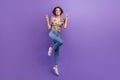 Full length portrait of active carefree person jumping demonstrate v-sign empty space on purple color